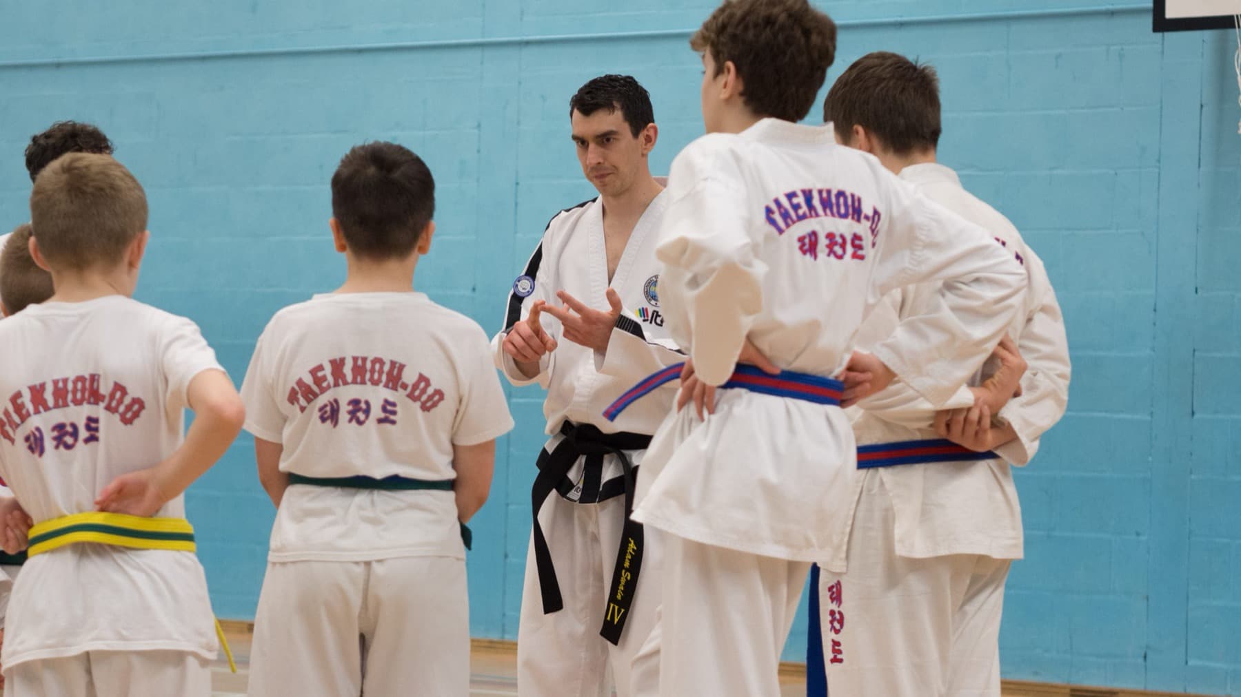 Junior students lined up with their instructor in a sports hall